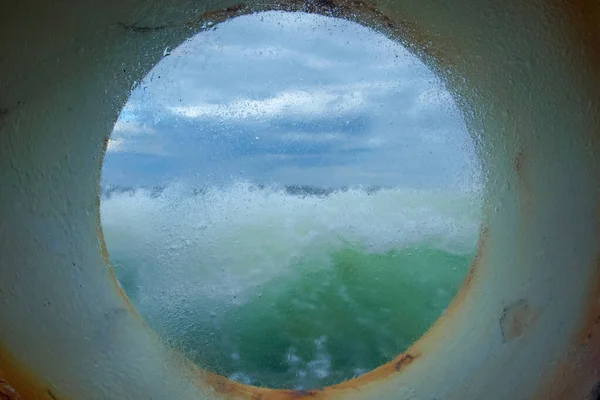 Tormenta en el mar a través del ojo de buey cubierto de hielo de la nave, la corrosión en las partes metálicas es visible, el Ártico . —  Fotos de Stock