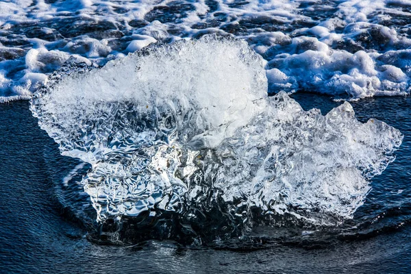 Ártico, um pedaço de gelo de alívio claro em uma praia de seixos nas ondas que se aproximam . — Fotografia de Stock