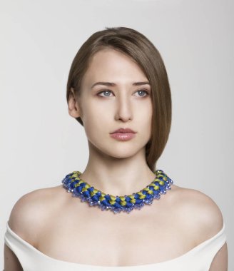 Güzel çekici esmer model kız beyaz izole mavi ve sarı kolye ile.