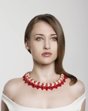 Güzel çekici esmer model kız beyaz izole kırmızı ve beyaz kolye ile.