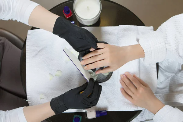Las manos de la mujer que reciben manicura y el procedimiento de cuidado de uñas de cerca —  Fotos de Stock