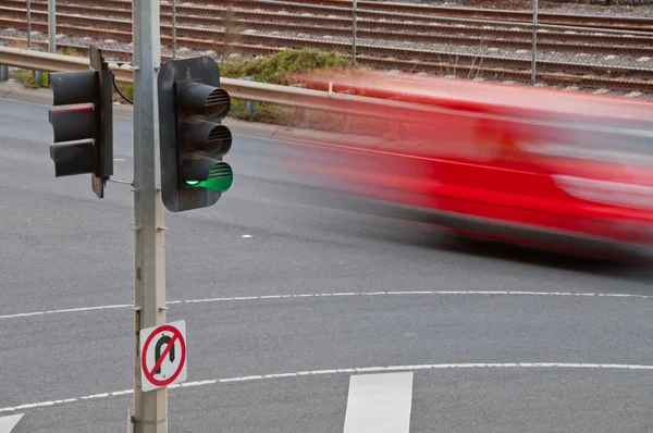 Spostamento auto rossa offuscata con palo semaforo verde — Foto Stock