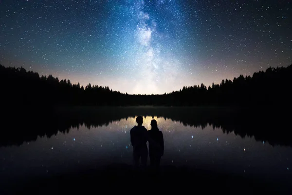 Pareja romántica bajo el cielo estrellado, la Vía Láctea se refleja en el lago — Foto de Stock