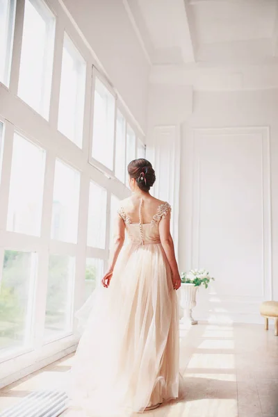 美丽迷人的新娘在豪华的礼服看。肖像的幸福新娘坐在白色的照片工作室的婚纱。年轻的吸引力新娘用花 — 图库照片