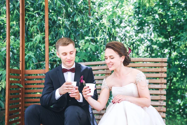 Jonge mooie bruid en bruidegom koffie drinken bij het openlucht café. Verheugd huwelijksfeest dag — Stockfoto