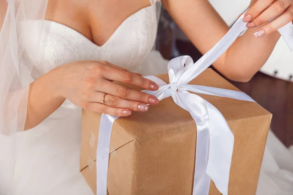 在婚礼庆典礼品盒的双手。工作室画像的美丽新娘的礼物。新娘紧握着礼物 — 图库照片