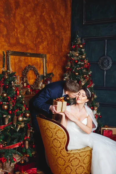Winter Wedding. Liefhebbers van bruid en bruidegom in Kerstdecoratie. Bruidegom Gift houden. romantische verrassing voor Kerstmis — Stockfoto