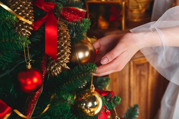 Topu elle. Genç kadın evde kırmızı topları ile Noel ağacı süsleme