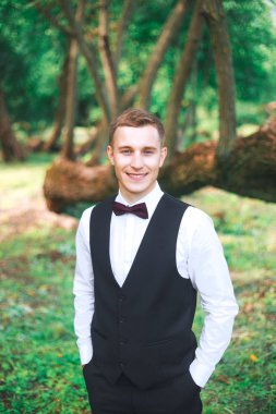  Düğün gününde damat. Muhteşem gülümseyen damat. gülümseyen ve gelin için bekleyen düğün smokin, ve damat. Zarif damat siyah kostüm ve papyon. İlik tutan takım elbiseli damat.