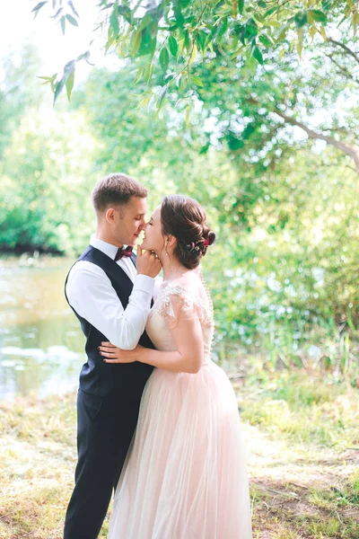 O noivo e a noiva juntos. abraços de casal. Dia do casamento. Bela noiva e elegante noivo andando após a cerimônia de casamento. Vestido de noiva de luxo e buquê de flores . — Fotografia de Stock