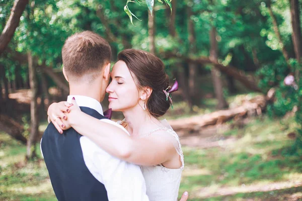 Novia y novio juntos. pareja abrazándose. Día de la boda. Hermosa novia y novio elegante caminando después de la ceremonia de la boda. Vestido de novia de lujo y ramo de flores . — Foto de Stock