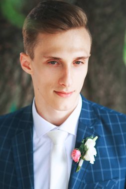 Muhteşem gülümseyen damat. Gülümseyen ve gelin için bekleyen düğün smokin, yakışıklı damat. Zarif adam mavi kostüm ve beyaz kravat.
