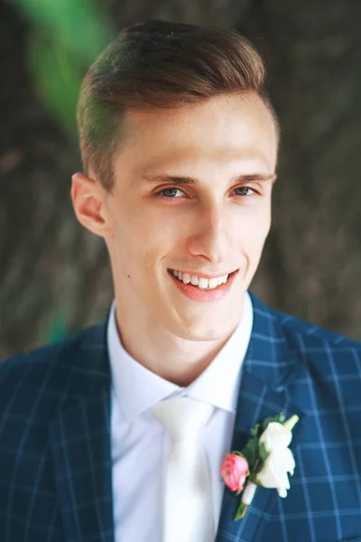 Precioso novio sonriente. novio guapo en esmoquin de boda sonriendo y esperando novia. Elegante hombre en traje azul y corbata blanca . —  Fotos de Stock