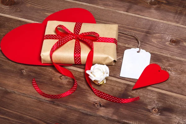 Wrapped vintage gift box with red ribbon bow and gift card  on wooden background — Stock Photo, Image