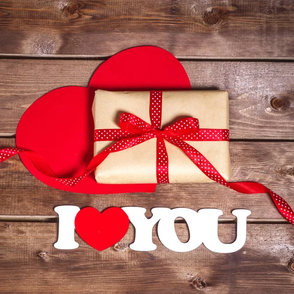 Gift and the words "I love you" on a wooden background . Valentines day red heart.  Valentine day card. — Stock Photo, Image