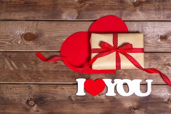 Gift and the words "I love you" on a wooden background . Valentines day red heart.  Valentine day card. — Stock Photo, Image