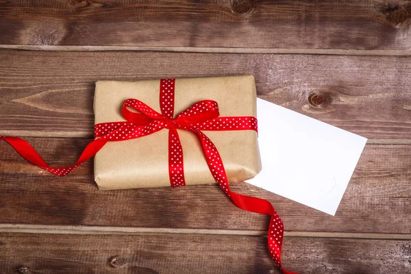 Wrapped vintage gift box with red ribbon bow and gift card  on wooden background — Stock Photo, Image