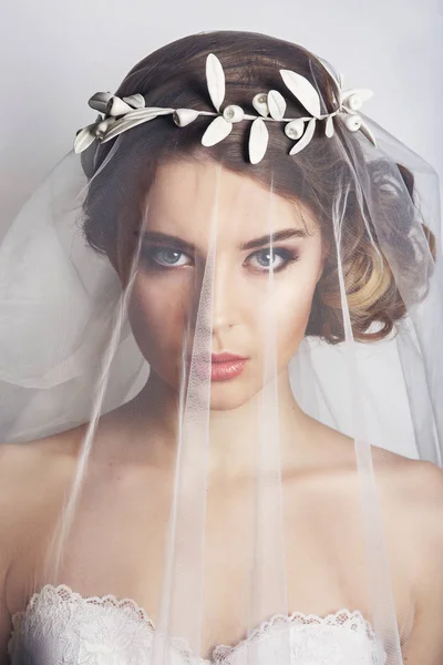 Beyaz arka planda moda düğün saç stili olan güzel bir gelin. Yakından güzel bir gelinin portresi. Düğün için. Stüdyo fotoğrafı. Yüzünde peçeyle güzel bir gelin portresi.