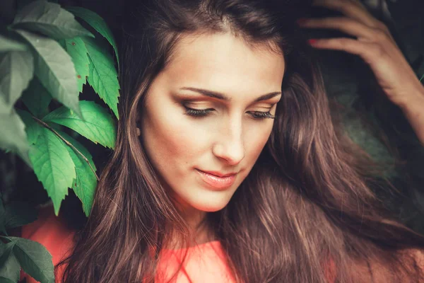 Feliz hermosa mujer joven en el parque de flores de primavera. Chica bonita con flores de primavera. Modelo de moda al aire libre — Foto de Stock