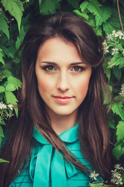 Feliz hermosa mujer joven en el parque de flores de primavera. Chica bonita con flores de primavera. Modelo de moda al aire libre — Foto de Stock