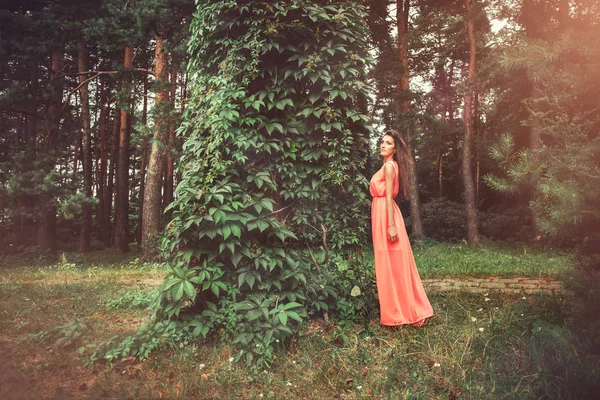 Feliz hermosa mujer joven en el parque de flores de primavera. Chica bonita con flores de primavera. Modelo de moda al aire libre — Foto de Stock