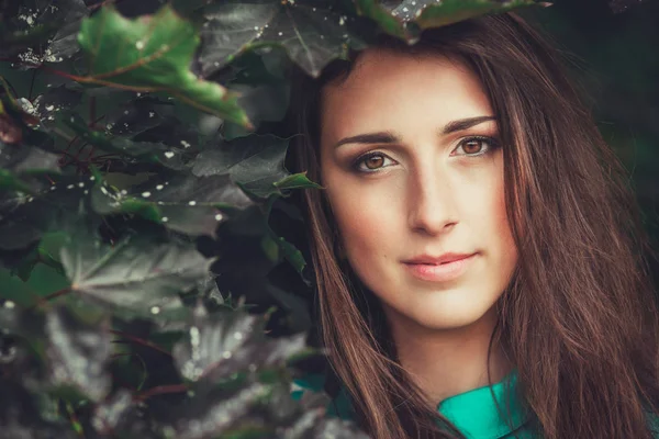 Feliz hermosa mujer joven en el parque de flores de primavera. Chica bonita con flores de primavera. Modelo de moda al aire libre — Foto de Stock