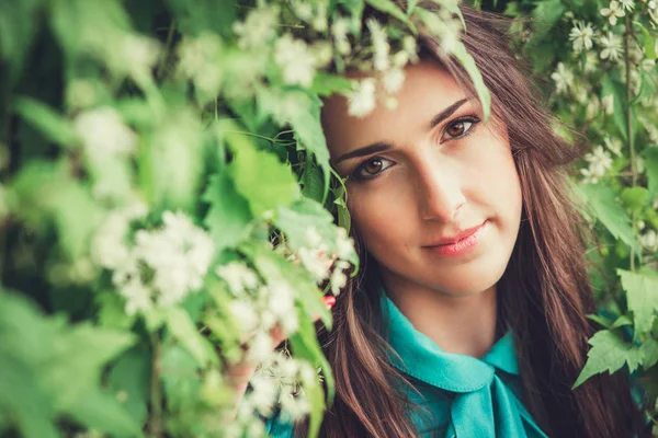 Feliz hermosa mujer joven en el parque de flores de primavera. Chica bonita con flores de primavera. Modelo de moda al aire libre — Foto de Stock