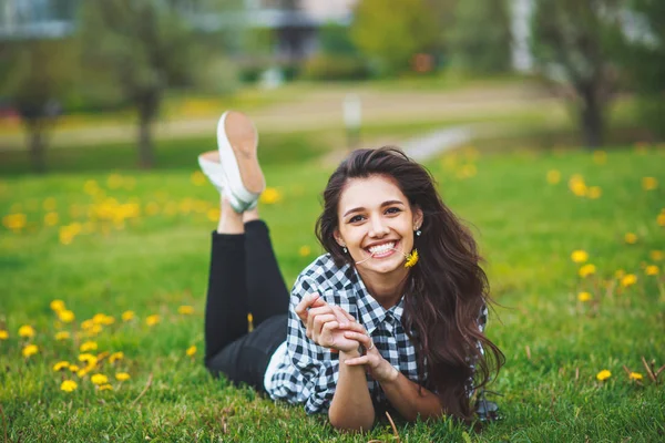 Mooie brunette vrouw houden een bloem in de tanden en glimlachen — Stockfoto