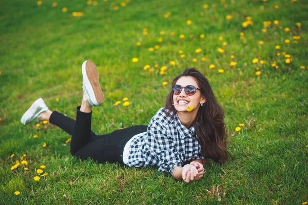 Dişlerini bir çiçek tutan ve gülümseyen güzel esmer kadın