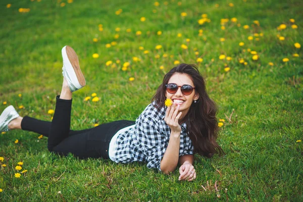 Dişlerini bir çiçek tutan ve gülümseyen güzel esmer kadın