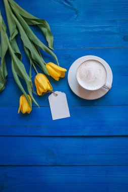 Sarı Lale ile kahve kupa çiçekler ve Günaydın mavi rustik masanın üzerine notlar
