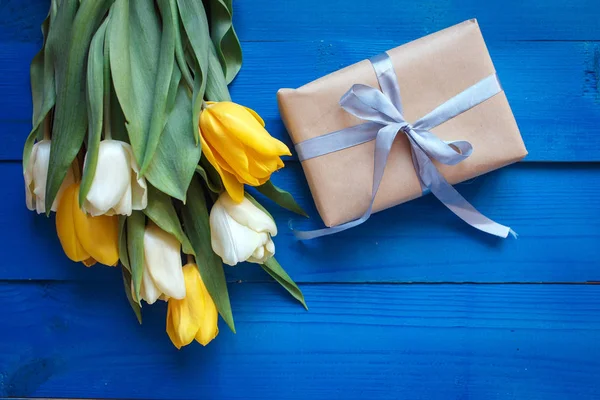 Lente tulp bloemen, doos van de gift op blauwe houten tafel van bovenaf in plat lag stijl. — Stockfoto