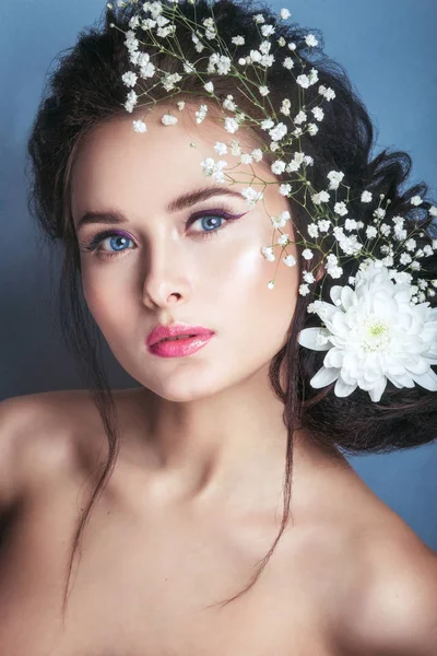 Retrato de una joven romántica con una flor blanca en el pelo mirando a la cámara. Primavera moda foto . — Foto de Stock