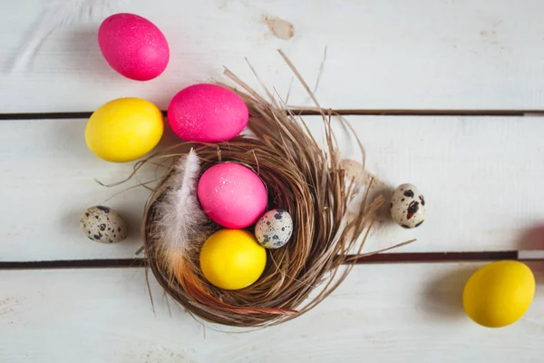 黄色和粉红色的鸡蛋复活节背景。与复制空间的顶视图。复活节彩蛋上质朴木板巢 — 图库照片