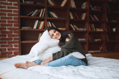 Sabahları evde yatakta yastık kucaklayan güzel genç kadın 