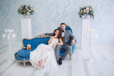 Gelin güzel elbise ve damat gibi beyaz studio iç içeride kanepe evde oturan gri elbiseli.