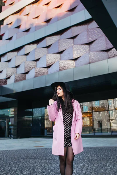Retrato al aire libre de una joven hermosa mujer de moda caminando por la calle. Modelo con elegante abrigo rosa, sombrero negro. Modelo mirando a un lado . — Foto de Stock