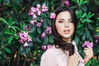 Etrafı çiçeklerle çevrili güzel bir kadının açık hava moda fotoğrafı. Bahar çiçekleri.