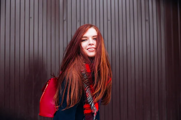 Zamknąć widok atrakcyjnych szczęśliwy kaukaskim kobieta z imbiru włosy sobie stylowe ubrania patrząc i uśmiechając się do kamery, pozowanie na ścianę. Pojęcie szczęścia i młodzieży — Zdjęcie stockowe