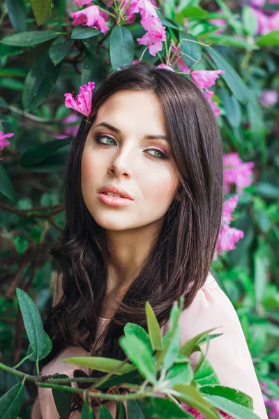 Retrato de una joven mujer hermosa posando entre árboles florecientes — Foto de Stock