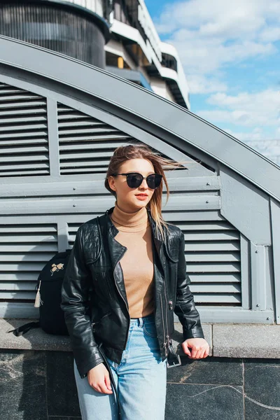 Fashion portrait pretty woman in black rock style in sunglasses over gray background in city
