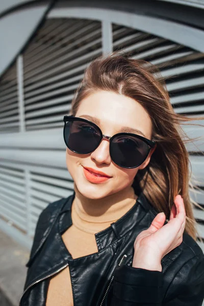 Retrato de moda mujer bonita en estilo rock negro en gafas de sol sobre fondo gris en la ciudad — Foto de Stock