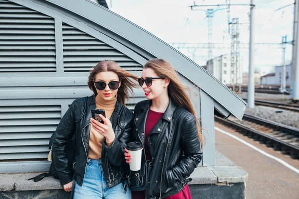 Dvě ženy mluví v City.Outdoor životní styl portrét dvou nejlepších přátel bokovky dívek nosí stylové kožené bundě a sluneční brýle s cofee, šílet a mají velký čas společně — Stock fotografie