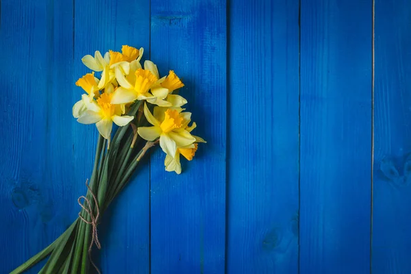 Gele narcissen boeket op blauwe houten achtergrond, Paaskaart — Stockfoto