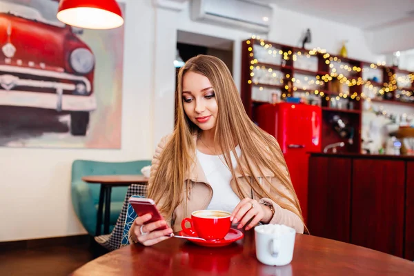 Glückliche Frau mit Smartphone beim Entspannen im Café nach einem Spaziergang während ihres Sommerwochenendes, charmant lächelnde Hipster-Mädchen erhielt gute Nachrichten auf dem Handy, während sie in einem gemütlichen Café sitzen — Stockfoto