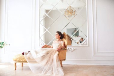 Gelin gibi beyaz studio iç içeride kanepe evde oturup güzel elbiseli. Moda düğün tarzı .