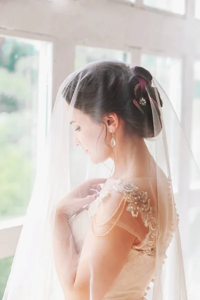 Hermosa novia joven con maquillaje de boda y peinado en bedroom.Beautiful retrato de novia con velo sobre su cara. Primer plano retrato de joven novia hermosa . — Foto de Stock