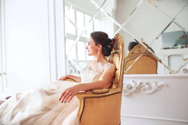 Sposa in bellissimo vestito seduto sul divano all'interno in interni monolocali bianchi come a casa. Stile di nozze alla moda  . — Foto Stock
