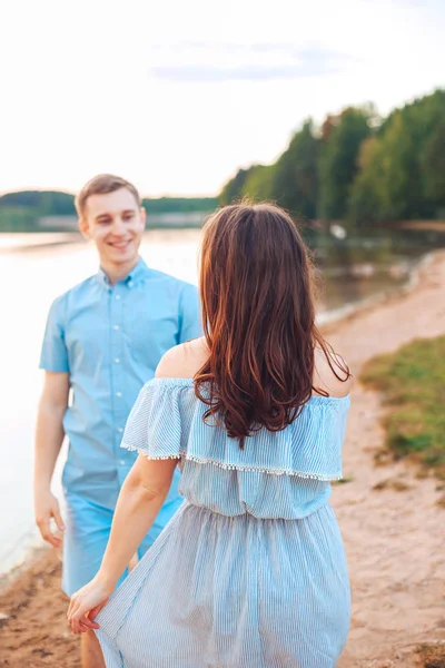 Jeune beau couple amoureux marchant sur la plage au coucher du soleil . — Photo