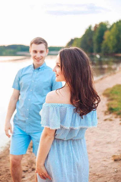 Pasangan muda yang cantik jatuh cinta berjalan di pantai saat matahari terbenam . — Stok Foto